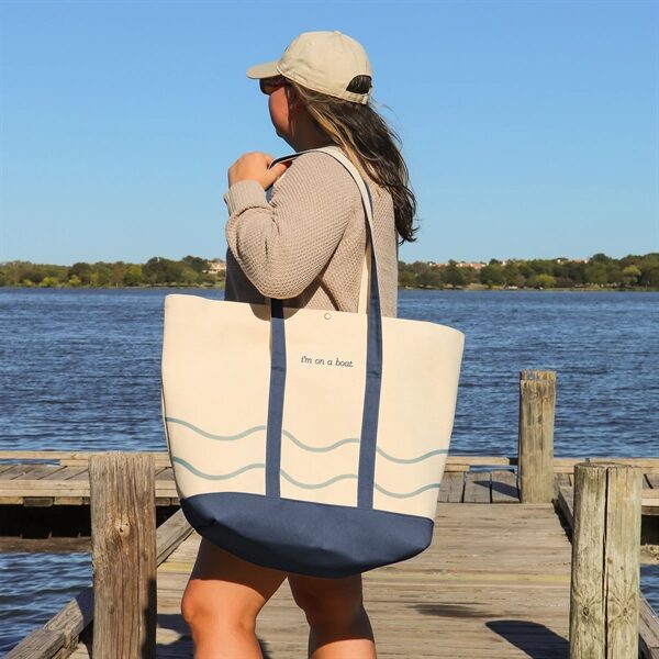 woman holding a tote bag made of heavy weight natural canvas with blue colored canvas trim with a snap closure